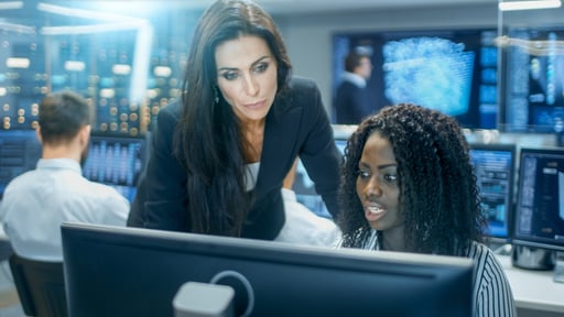 Female-Team-Leader-Consults-Young-Computer-Engineer.-They-Work-in-a-Crowded-Office-on-a-Neural-Network-Artificial-Intelligence-Project.-866661062_5120x2880